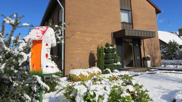 A two-story brick house with a modern design, a front porch, and a snow-covered garden. - Ferienwohnung Miezal, 1-4 Pers (Raesfeld)