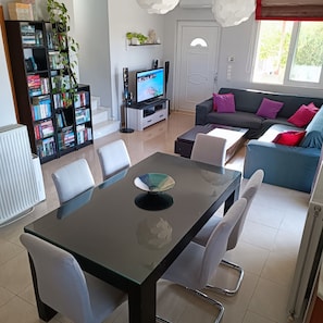 Relax in this stylish living room with a glass-top dining table, flat-screen TV, and comfortable sofa.