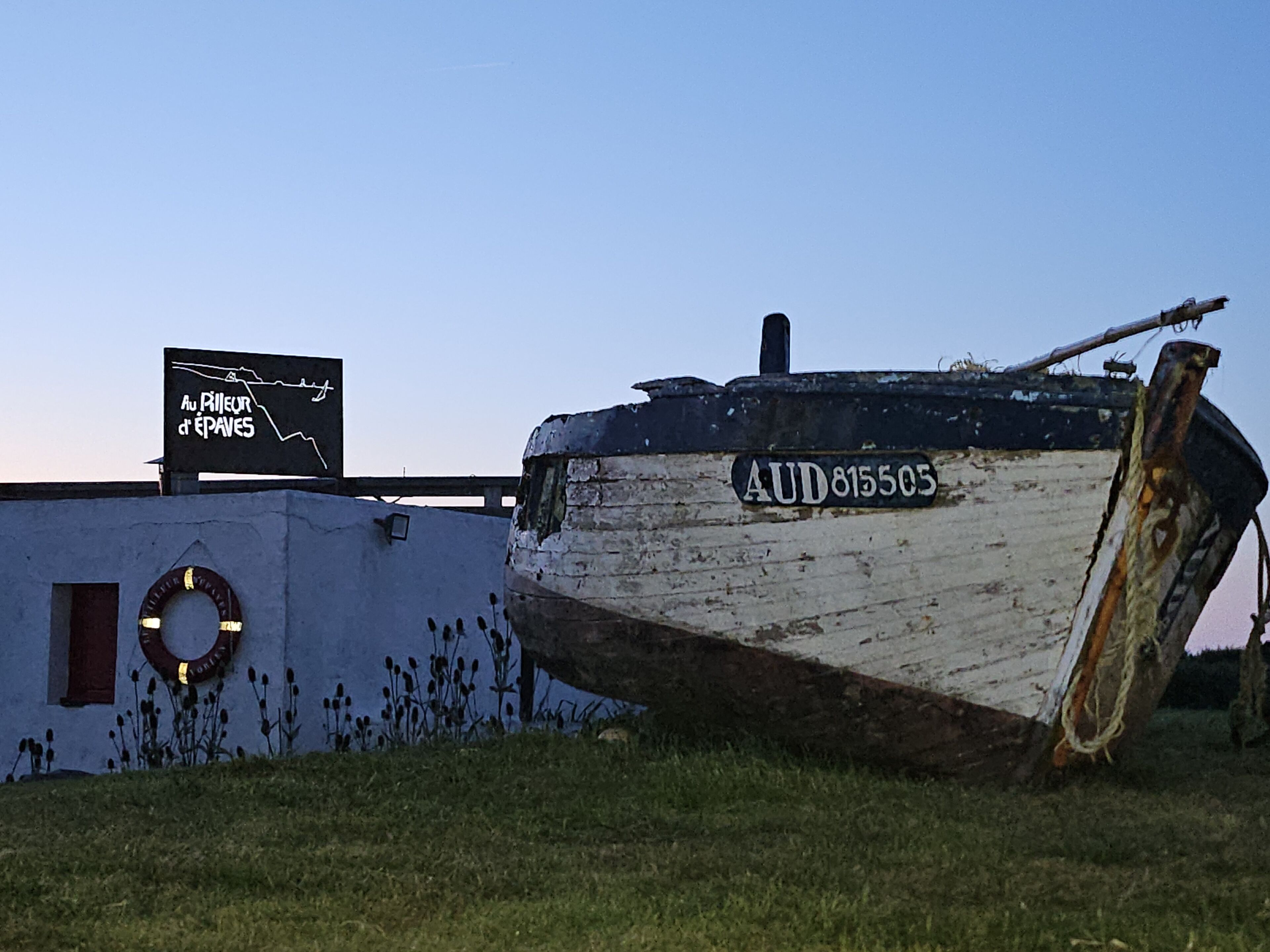Un bateau portant le numéro AUD815505 était amarré près d’un bâtiment sur lequel on pouvait lire l’inscription « Au P’tit Épave ».