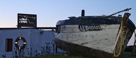 Un bateau portant le numéro AUD815505 était amarré près d’un bâtiment sur lequel on pouvait lire l’inscription « Au P’tit Épave ».