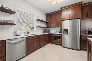 A modern kitchen with wooden cabinets, stainless steel appliances, and a white countertop. - Hyde Park Home - Walk to Nelson + Streetcar 1078 (Kansas City)