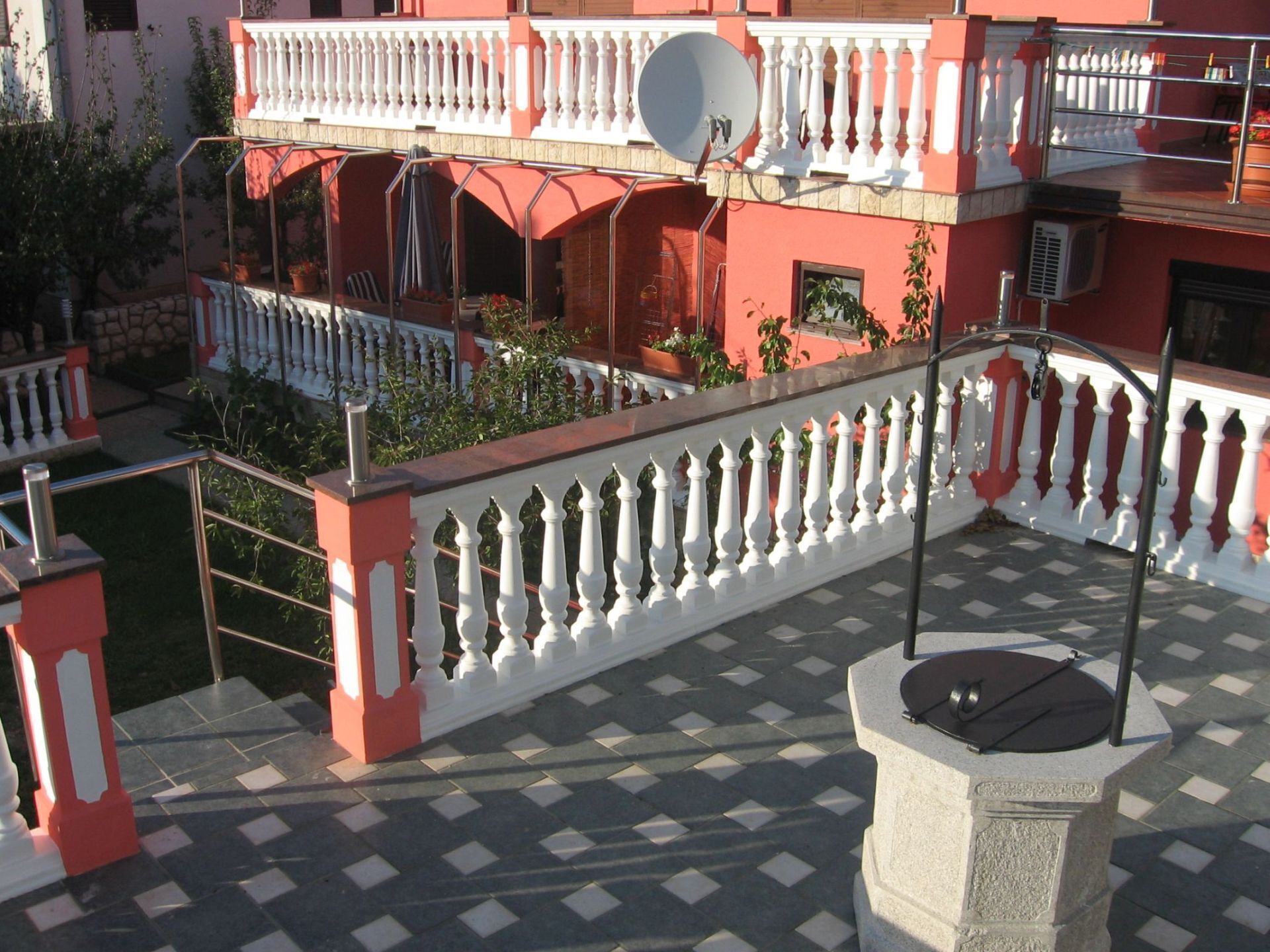 Un immeuble à plusieurs étages doté de balcons, d’une antenne parabolique et d’une terrasse dallée.