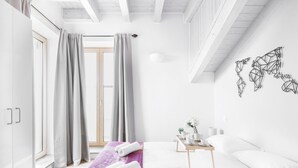 Una habitación de hotel moderna con una cama grande, una mesita de noche de madera, una ventana con cortinas y una obra de arte abstracto colgada en la pared.