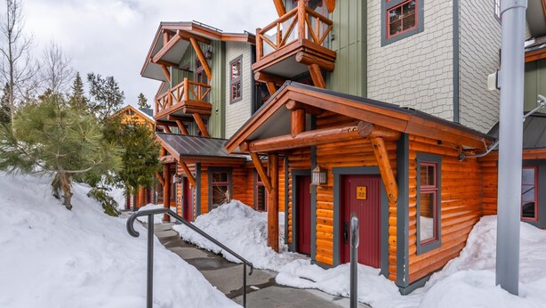 A log cabin-style building with a red door, a balcony, and a staircase leading to the entrance. - Home Near Sierra Golf Course! Just a Short Walk to the Shuttle! (Mammoth Lakes)