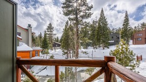 A wooden balcony railing overlooking a snowy landscape with trees and buildings. - Home Near Sierra Golf Course! Just a Short Walk to the Shuttle! (Mammoth Lakes)