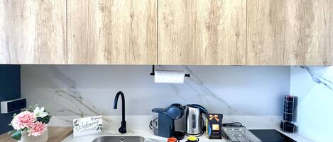 A modern kitchen with a marble countertop, stainless steel sink, and wooden cabinets.