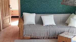 Ett mysigt rum med en soffa, ett runt träbord och en stol.
