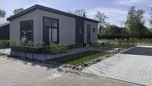 A modern building with a flat roof, large windows, and a small garden area with a water feature. - De Noordzee by Interhome (Scherpenisse)