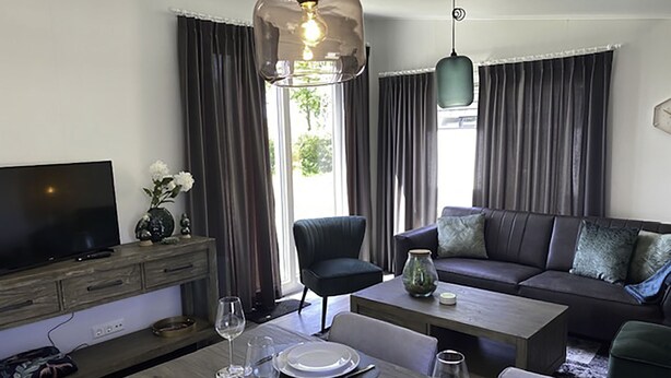 A modern living room with a dining area, a sofa, a TV, and a chandelier. - De Noordzee by Interhome (Scherpenisse)