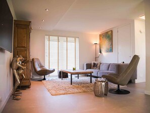 A modern living room with a sofa, two armchairs, a coffee table, and a decorative metal sculpture.