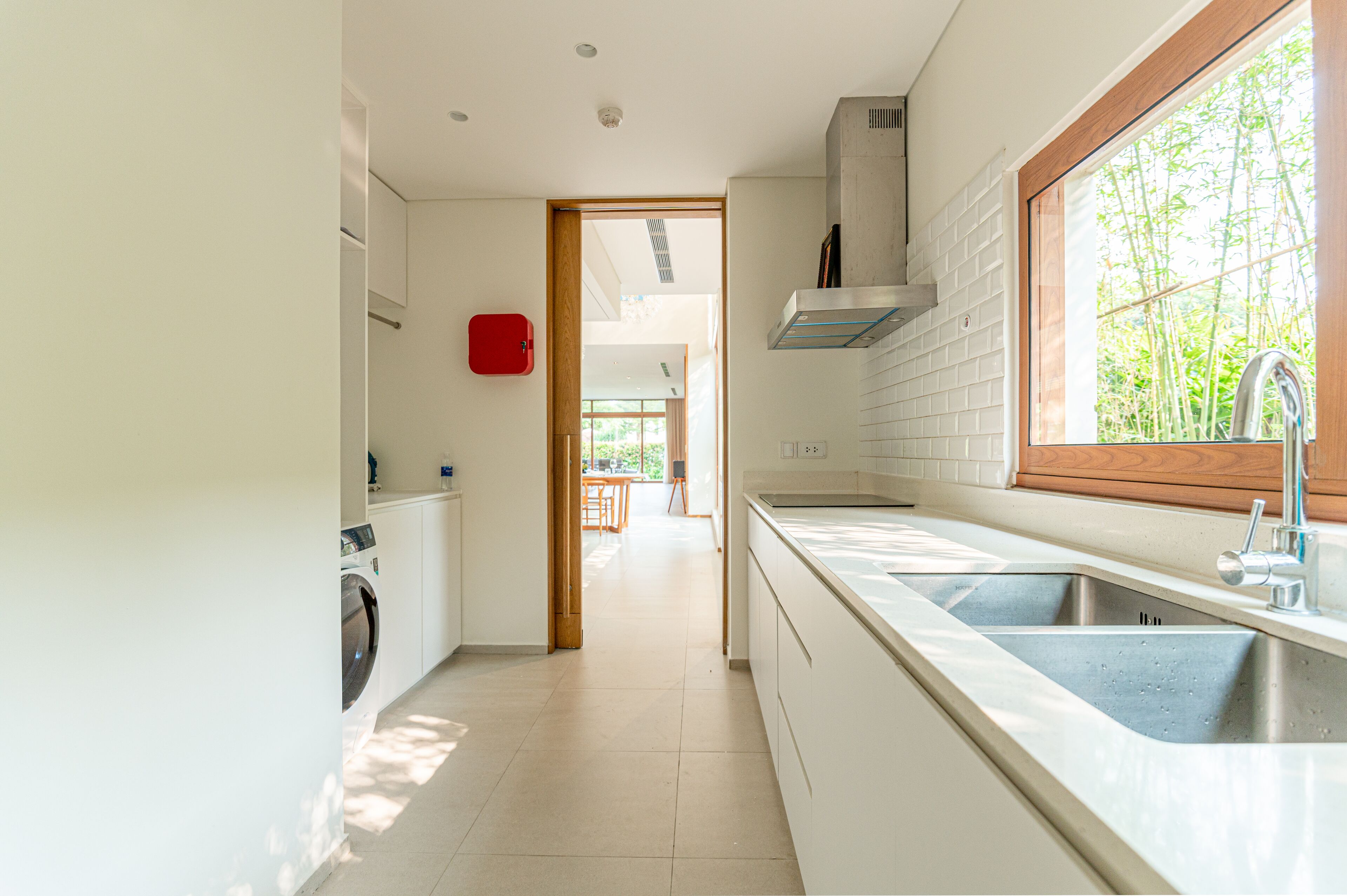 A modern kitchen with a large window, a built-in washing machine, and a view of the outdoors.