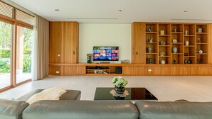A modern living room with a large flat-screen TV, wooden shelving, and a sofa. - 5BRs villas for a perfect family getaway (Da Nang)