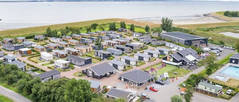 Un quartier résidentiel avec des maisons modernes, une piscine et une plage en arrière-plan.