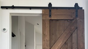 A hallway with a wooden barn-style door and a sliding barn door. - De Parel by Interhome (Scherpenisse)