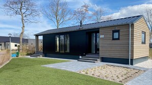 A modern house with a dark facade, large windows, and a sloped roof. - De Parel by Interhome (Scherpenisse)