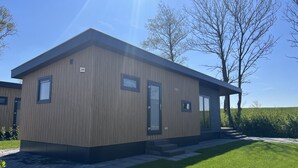 Een modern, gelijkvloers gebouw met een houten gevel, een deur en een klein raam.