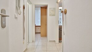 A hallway with a telephone, a door, and a window with curtains. - Die Insel Appartement 19 (Timmendorfer Strand)