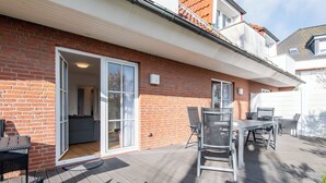 A patio with a table and chairs, a sliding glass door, and a brick wall. - Sonnig. Terrasse. Zentral (Westerland)