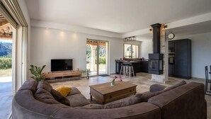 Un salón amplio con un sofá grande, una mesa de centro y un televisor. Cuenta con una zona de cocina con estufa y una mesa de comedor.