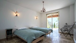 Un dormitorio con dos camas, una mesita, una silla y vistas al exterior.
