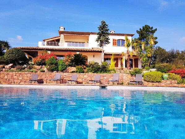 A two-story house with a swimming pool in front.
