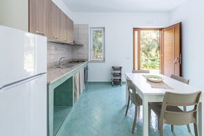 Een koelkast, een oven, een kookplaat, kookgerei, borden en bestek