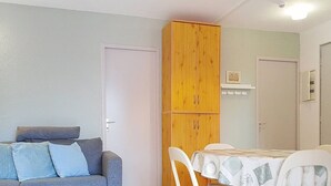 A compact living space with a sofa, dining table, chairs, and a wooden wardrobe. - Air-Conditioned T2 with Parking, Bormes-les-Mimosas (Bormes-les-Mimosas)