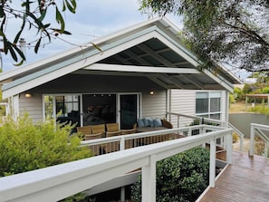 Uma casa moderna com alpendre, deck e uma grande janela com vista para um jardim.