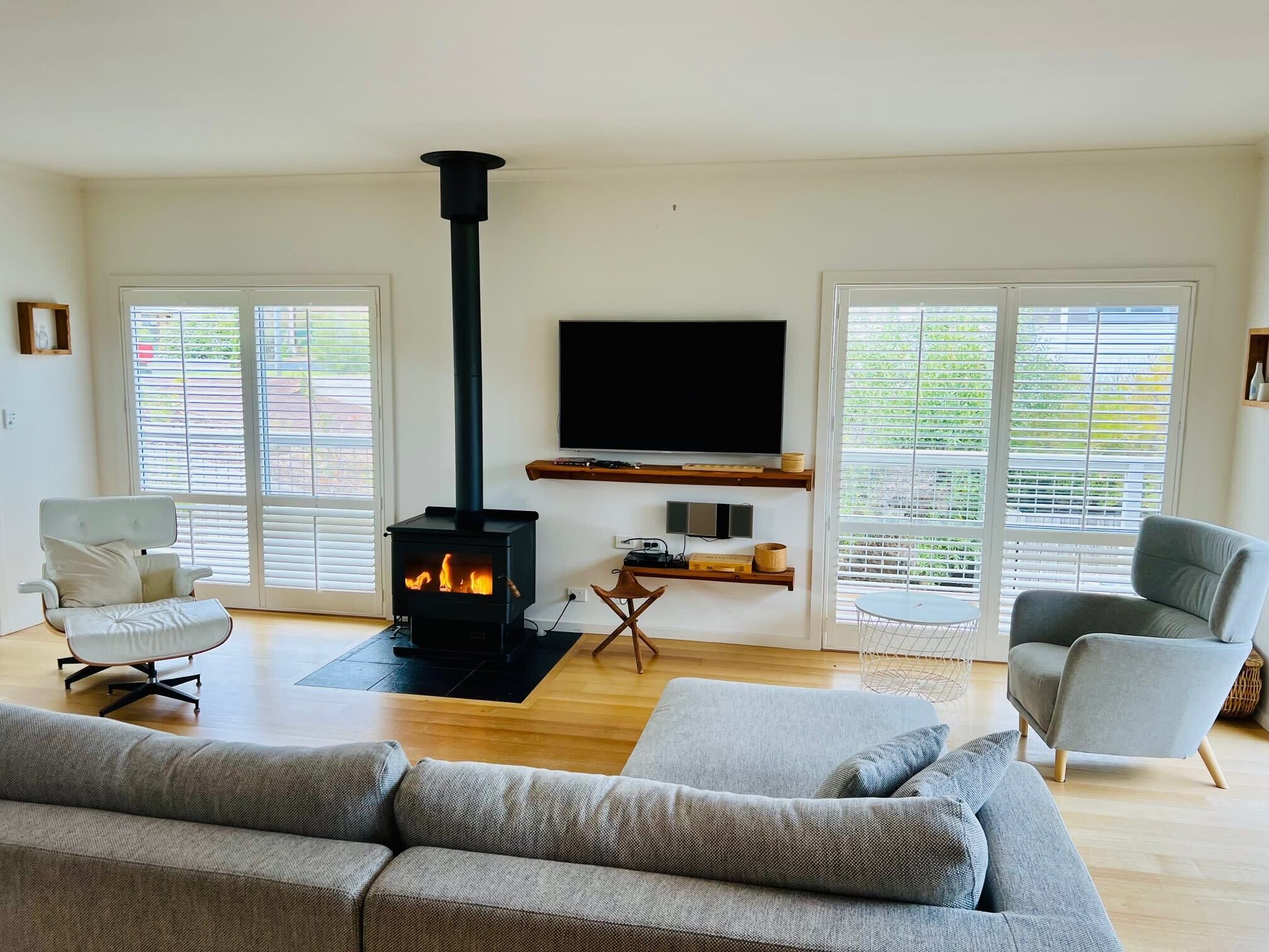 A modern living room with a wood-burning stove, a flat-screen TV, and two sofas.