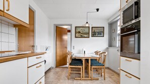 Une cuisine compacte avec des meubles de rangement en bois, une table à manger avec des chaises et un four à micro-ondes.