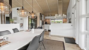 A modern kitchen with white cabinets, a stainless steel refrigerator, and a large island.
