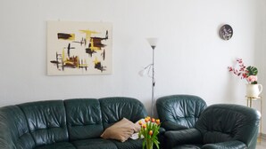 Ein modernes Wohnzimmer mit einem grünen Ledersofa, einem Glastisch und einer dekorativen Vase mit Blumen.