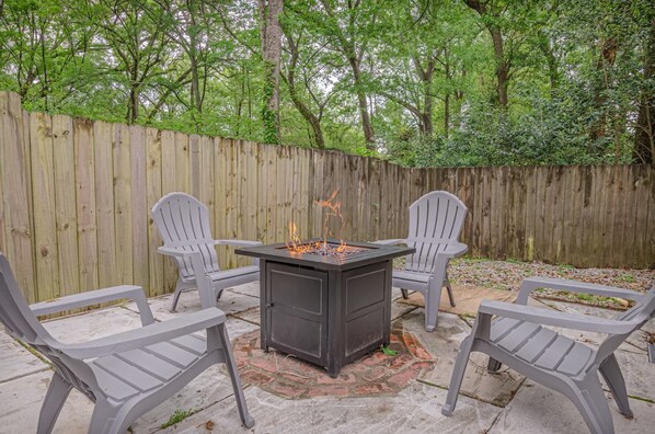 Une terrasse dotée d’un foyer extérieur en métal, entourée de quatre fauteuils Adirondack.
