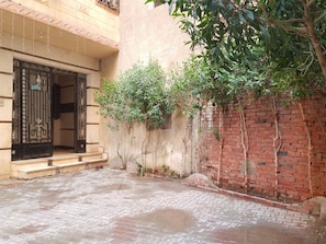A courtyard with a paved floor, a black gate, and a brick wall.