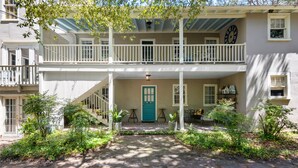 A two-story building with a front porch, a green door, and a clock on the second floor. - The Heart of Historic Charleston | The Mod Suite (Charleston)