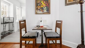 A dining area with a table set for two, featuring a painting above and a floor lamp to the side. - The Heart of Historic Charleston | The Mod Suite (Charleston)