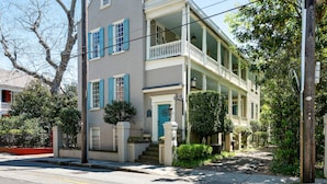 A two-story house with a balcony, a front door, and a staircase leading to the entrance. - The McKenzie Suite at The Mary Scott House (Charleston)