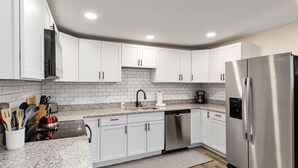 A modern kitchen with white cabinets, a stainless steel refrigerator, and granite countertops. - Pondview 4BR Cabin-Walk to Caverns, Hot Tub, Wi-Fi (Luray)