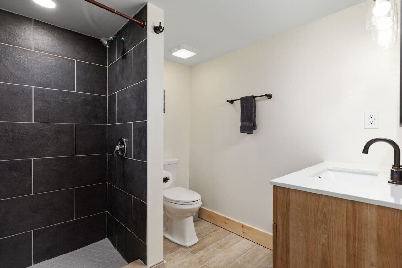 A modern bathroom with a shower, toilet, and sink.