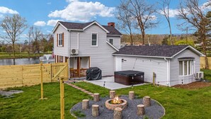 A two-story house with a fire pit in the backyard, a hot tub, and a fenced pond. - Pondview 4BR Cabin-Walk to Caverns, Hot Tub, Wi-Fi (Luray)