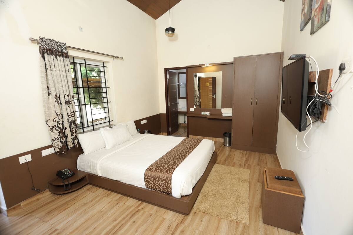 A bedroom with a bed, bedside table, and a TV mounted on the wall.