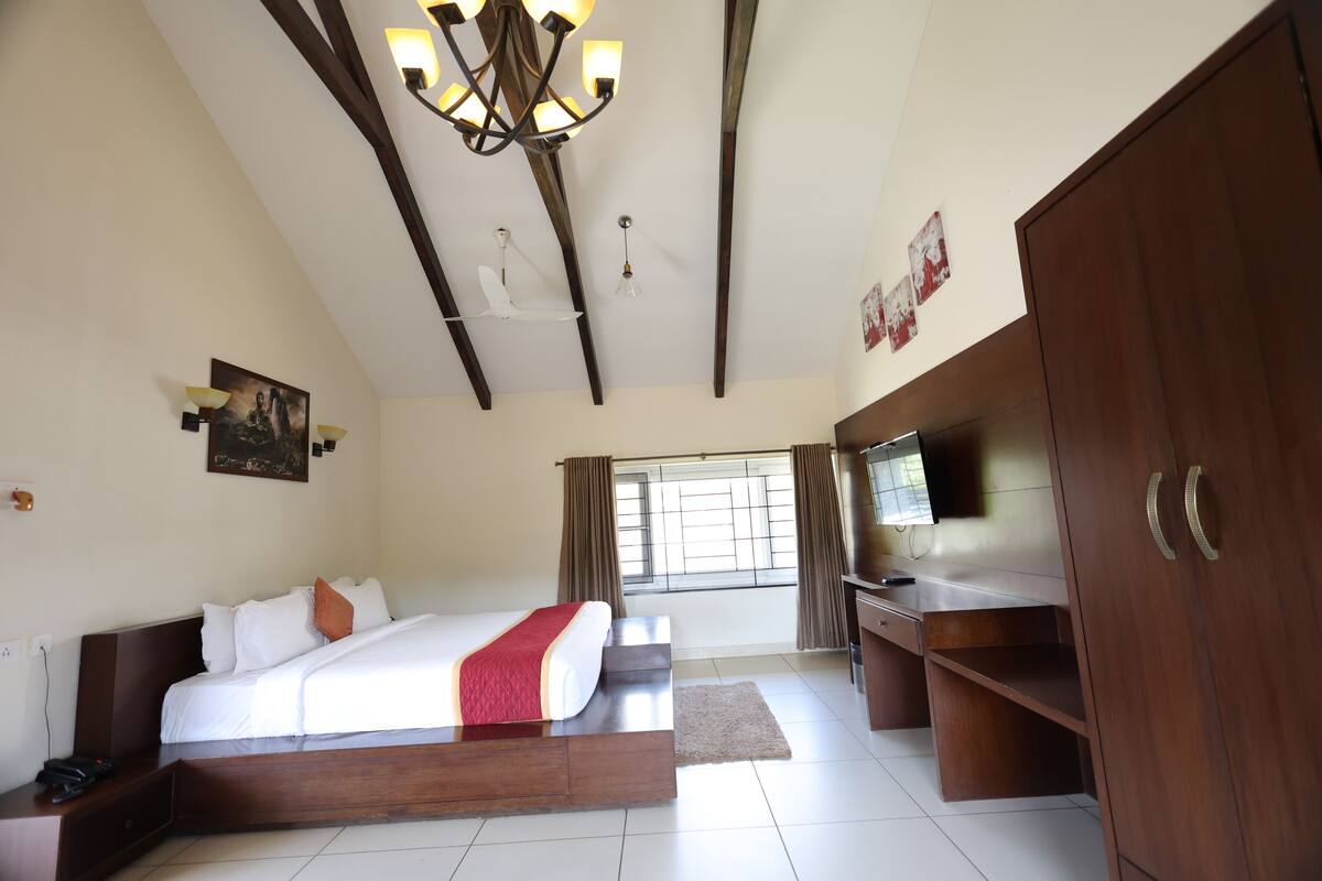 A hotel room with a bed, a TV, a desk, and a wardrobe.