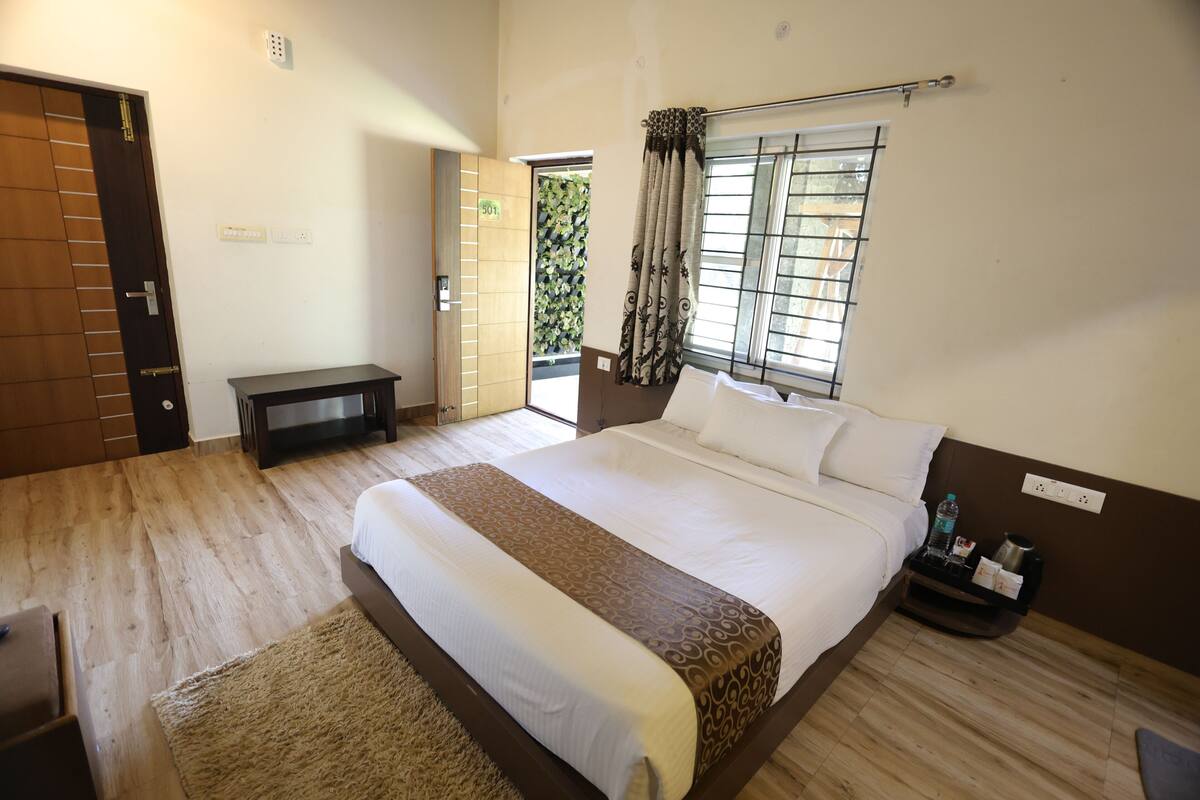A bedroom with a large bed, bedside table, and a window with curtains.