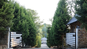 A stone building with a metal gate, surrounded by tall evergreen trees. - Yercaud Yellow Lake Resorrt and spa (Yercaud)