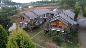 A large, multi-story house with a spacious outdoor area, multiple balconies, and a well-maintained garden. - Yercaud Yellow Lake Resorrt and spa (Yercaud)