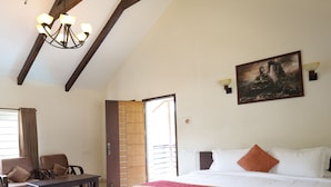 A spacious bedroom with a large bed, a wooden bench, a desk, and a chair. - Yercaud Yellow Lake Resorrt and spa (Yercaud)
