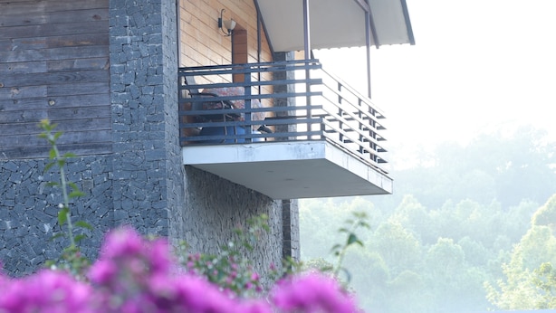 A modern building with a stone facade, a balcony with a metal railing, and a white awning. - Yercaud Yellow Lake Resorrt and spa (Yercaud)