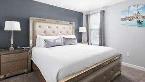 A neatly arranged bedroom with a large bed, two bedside tables, and a nightstand. - NEW! Gamers Paradise, Sauna, Theater, Pool/Spa, ChampionsGate, 8 Bed Luxury Home (Four Corners)