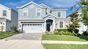 A two-story house with a garage, a front entrance with an arch, and a small front yard with grass and shrubs. - NEW! Gamers Paradise, Sauna, Theater, Pool/Spa, ChampionsGate, 8 Bed Luxury Home (Four Corners)