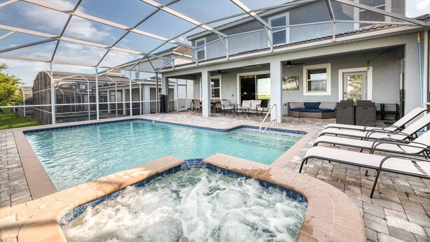 A covered outdoor swimming pool with lounge chairs and a hot tub. - NEW! Gamers Paradise, Sauna, Theater, Pool/Spa, ChampionsGate, 8 Bed Luxury Home (Four Corners)